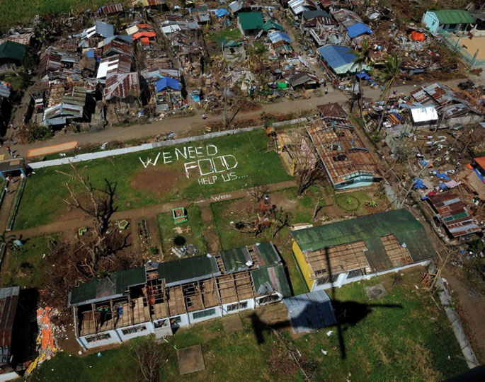 New York Daily Newsek Interneten daukan argazki honetan, Filipinetako herrixka zehaztu gabea, Haiyan tifoiak beste asko legez suntsitu ostean, 2013ko azaroan. Zelaian herritarrek 