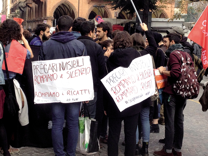 Jamie Mackay kazetari britainiarrak Open Democracyn plazaratu argazkian, gazte italiarrak Erromako kale okupazio batean joan den azaroaren 16an. Soinean daramatzaten afixatan diote: “Prekario ikusezinak”, “Hautsi dezagun isiltasuna”, “Hautsi dezagun xanta