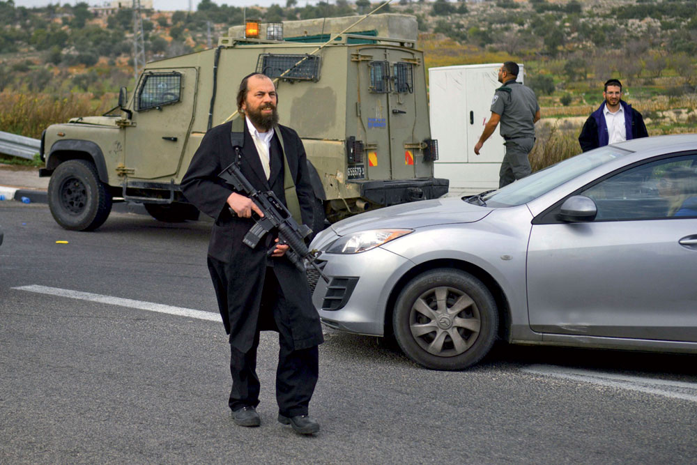 AP agentziak banatutako argazkian, israeldar kolono ultraortodoxo armatua militarrekin elkarlanean Zisjordaniako errepide batean, 2014ko udazkenean. Israelek segurtasun teknologia aspalditik esportatzen du mundu osora eta orain, Ekialde Hurbileko gatazken
