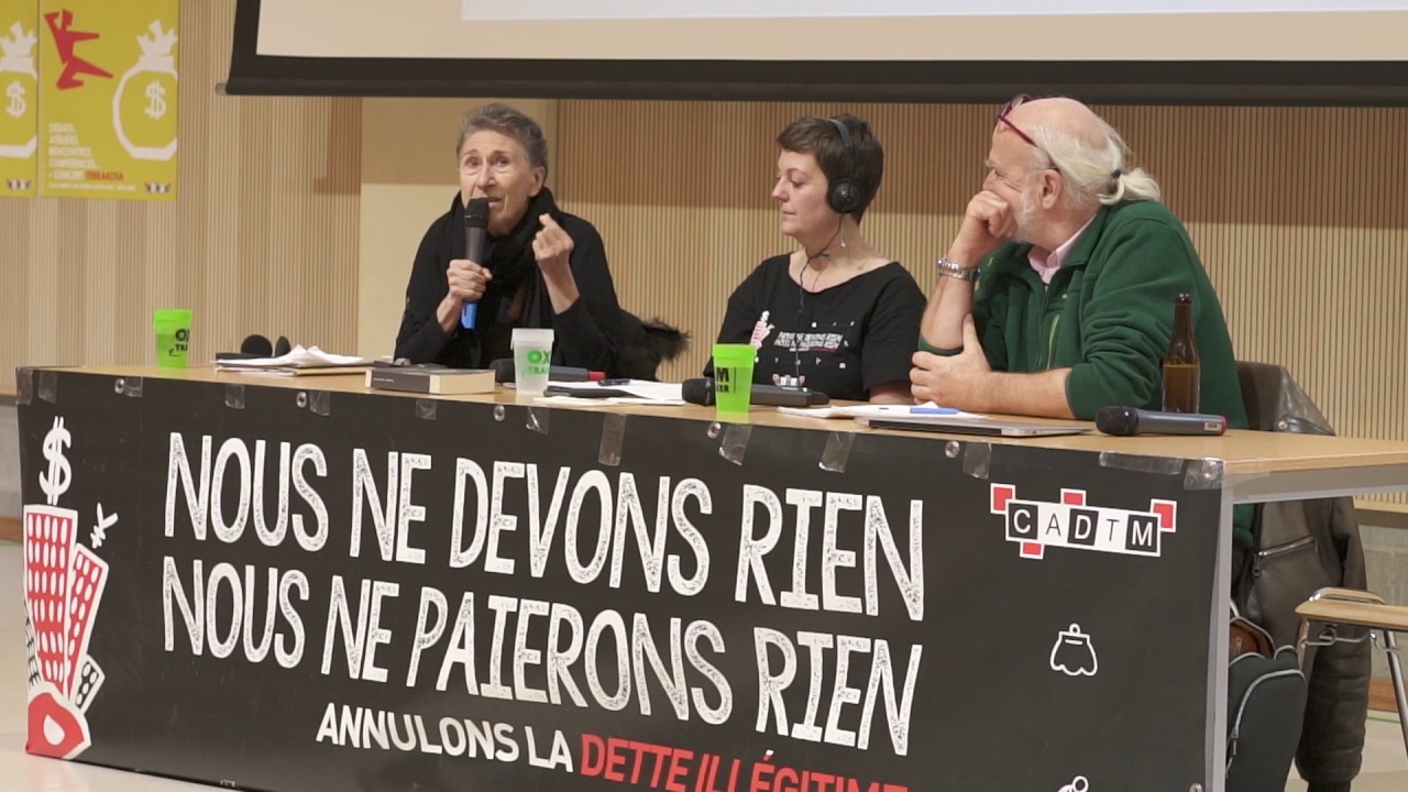 CADTMk interneten jarritako bideotik hartu irudian, ezkerretik hasita Silvia Federici hizketan, Noëmie Cravatte eta elkartearen fundatzaile Eric Toussaint, Bruselan abenduaren 6an burututako 8 orduko eztabaida maratoian. Mahaian idatzirik: “Ez dugu ezer z